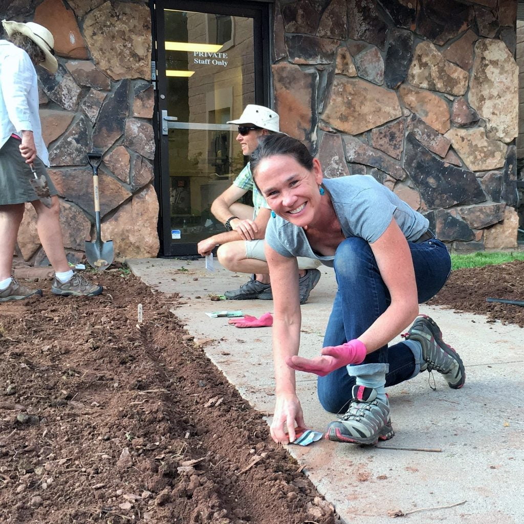 Woman smiling at the camera working in a garden.