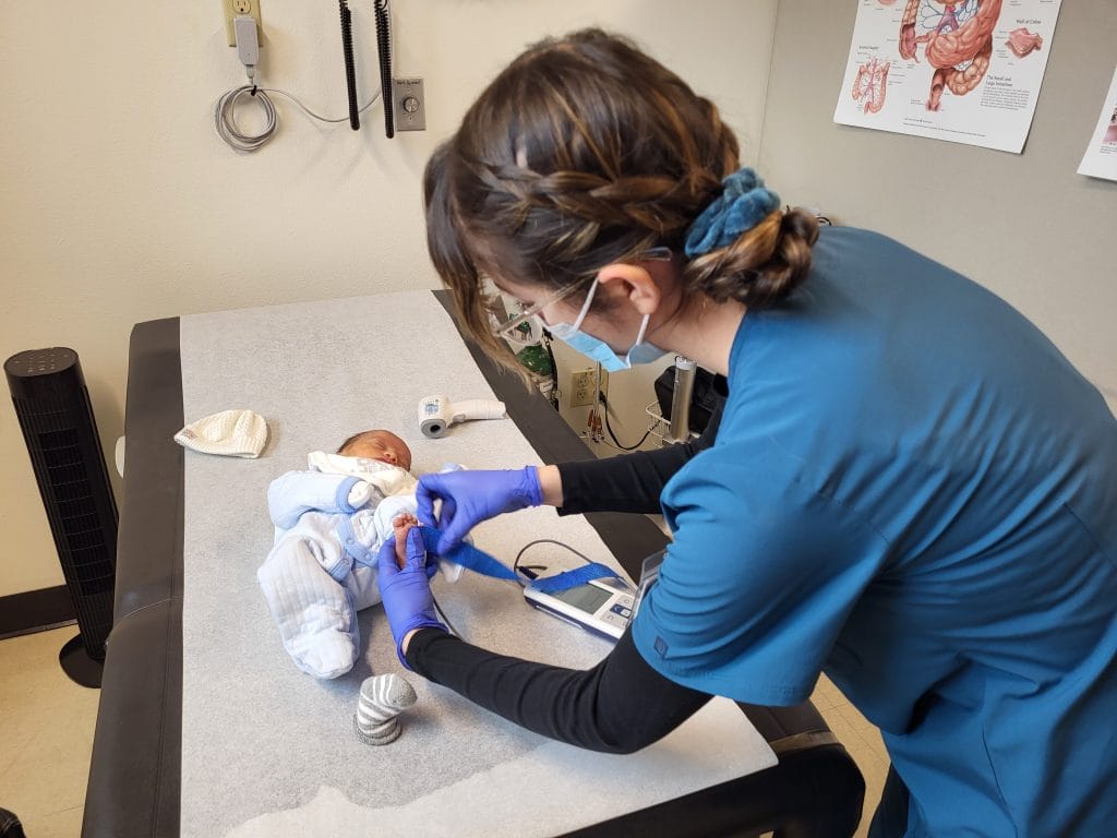 A healthcare professional is examining a baby on a medical table.