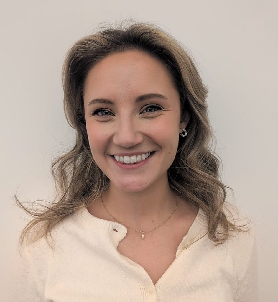 A person is smiling at the camera against a plain background.