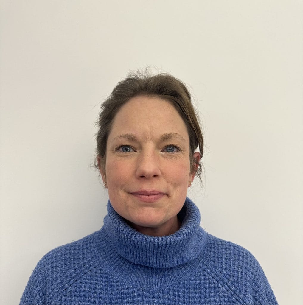A person wearing a blue turtleneck sweater against a plain background.